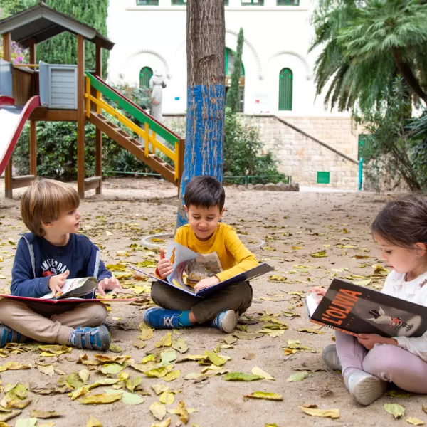tres infants llegint al pati de la sorra