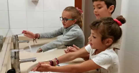Nenes i nen de 2n de primària rentant-se les mans explicant com hem de fer-ho per estalviar aigua