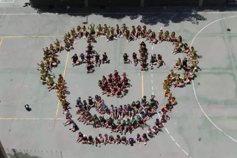 Imatge de l'Escola d'Estiu de Casp, amb nens i nenes formant una cara al pati