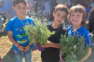 Alumnes amb les plantes de la celebració de la Pasqua, cuidades durant la Quaresma, per plantar al pati de l'escola