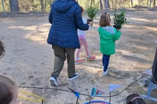 Alumnes d'infantil agafant les plantes per la la plantada al pati de l'escola en celebració de la Quaresma