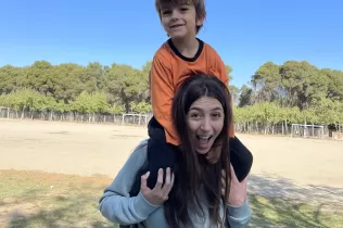 Alumne d'infantil i alumna de Batxillerat al pati de l'escola compartint l'activitat de Pasqua amb una plantada, jocs i activitats