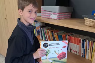 Alumne de 4t de primària guardant a la biblioteca el llibre de Sant Jordi regalat per l'escola a la seva classe