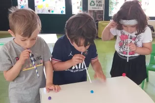 Nens i nenes de P4 fent experiments d'aire amb canyetes i una bola per treballar aquelles coses que existeixen però que no podem veure
