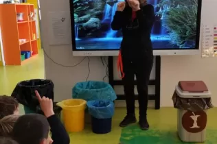 L'Alícia, cap de manteniment, explica als i les alumnes quins objectes i materials van a cada paperera per a fer un bon reciclatge