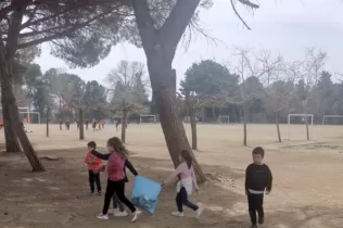 Nens i nenes de MOPI P5 recorren el pati de l'escola pe identificar i recollir la brossa que no ha estat degudament depositada a les papereres