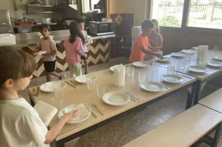 Nens i nenes de 2n de primària parant la taula per dinar a la granja escola de La Manreana