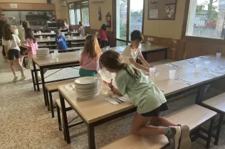 Nens i nenes de 2n de primària recollint la taula després de dinar a la granja escola de La Manreana