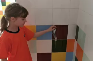 Alumna de 2n de primària tancant una aixeta que goteja com a mesura d'estalvi d'aigua
