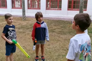 Nens de 2n de primària jugant amb pistoles d'aigua i un altre nen els explica que és una manera de malbaratar l'aigua