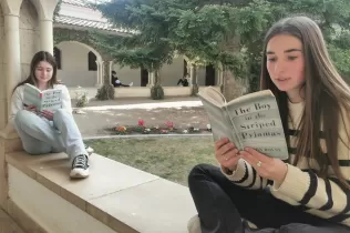 Alumnes llegint el llibre en anglès The Boy in the Stripped Pijamas al claustre de recepció de l'escola