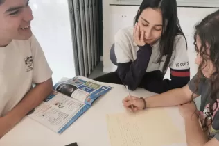 Alumnes a l'aula en la matèria d'anglès treballant en equip un text escrit.