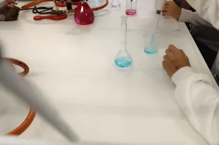 Alumnes de 1r ESO fent experiments científics guiats per l'alumnat de 1r Batxillerat al laboratori de l'escola en el marc de la Setmana de la Ciència