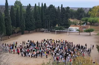 Alumnes de la NEI, amb educadores i educadors de l'etapa, al pati de l'escola ballant la correografia conjunta amb una canço de la Castanyada