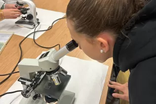 Alumnes de 1r ESO fent experiments científics guiats per l'alumnat de 1r Batxillerat al laboratori de l'escola en el marc de la Setmana de la Ciència