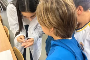 Alumnes de 1r ESO fent experiments científics guiats per l'alumnat de 1r Batxillerat al laboratori de l'escola en el marc de la Setmana de la Ciència