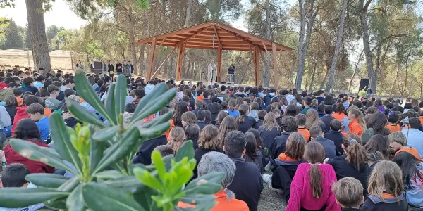 Alumnes de tots els cursos a l'Aula Natura Pare Ignasi Salat al pati de l'escola  celebrant la Pasqua en comuitat amb una plantada de plantes